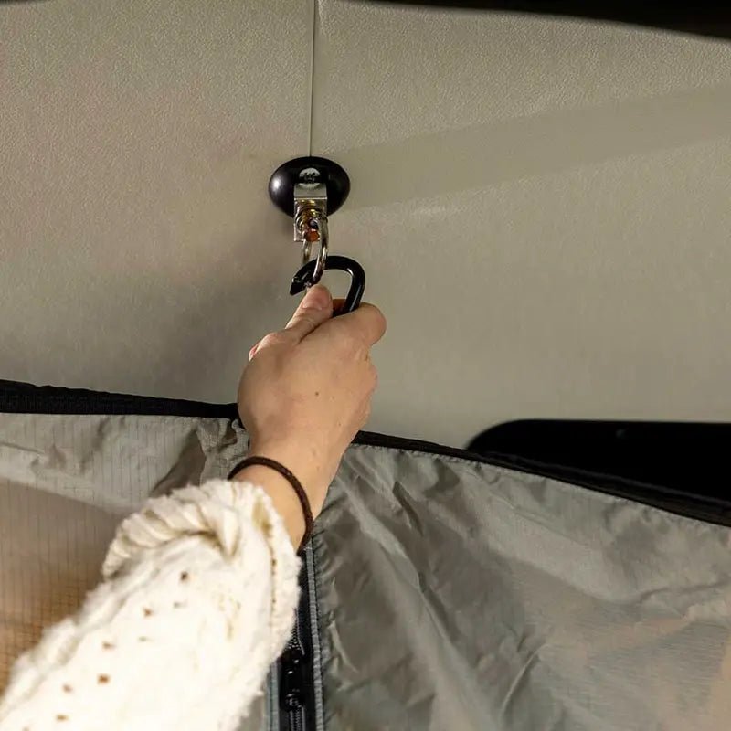 Securing the portable shower system to a ceiling-mounted hook inside the camper van.