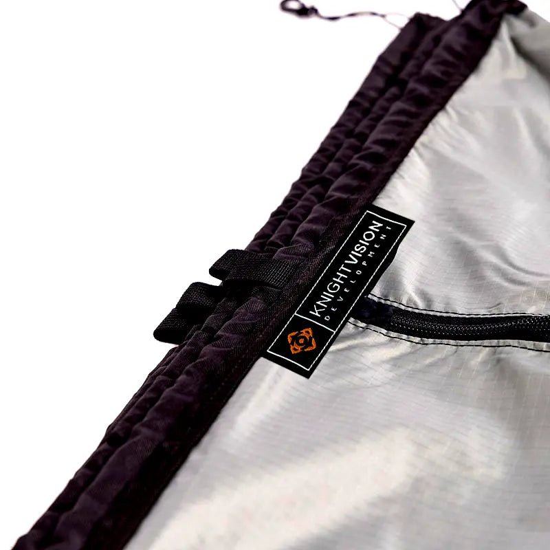 Close-up of the Knight Vision Development logo and zipper on the portable shower curtain material.