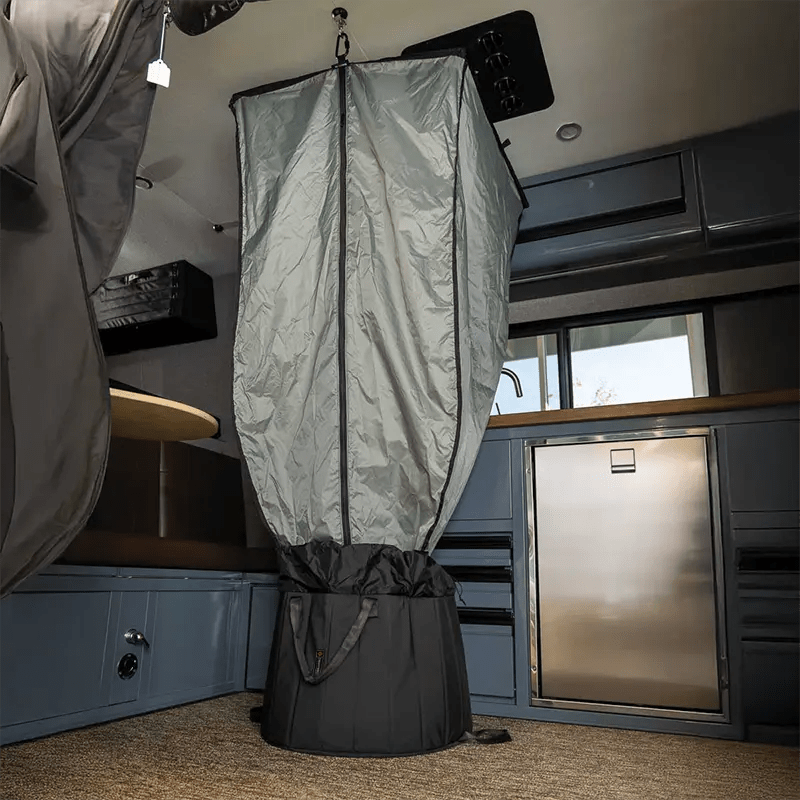 The portable shower system fully set up and hanging inside an adventure van interior.