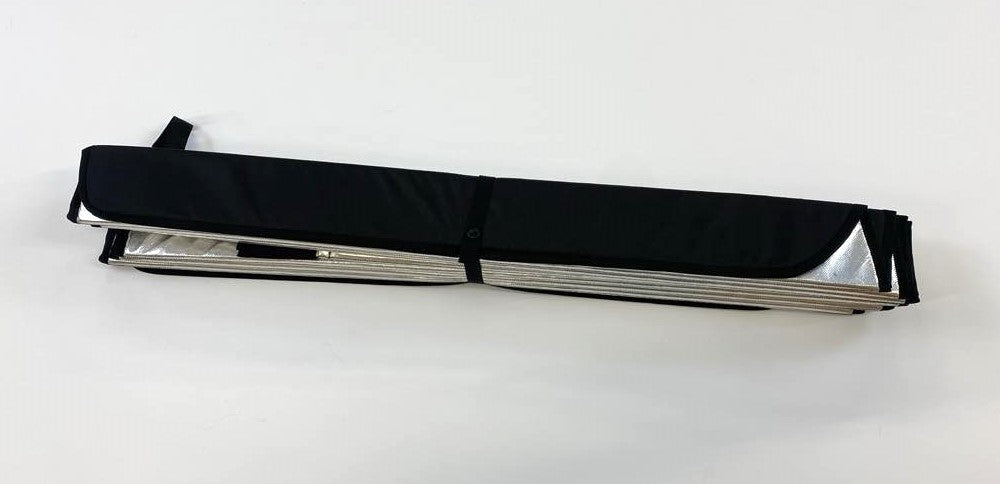 Folded insulated window cover secured with a black strap, revealing the reflective silver interior edges.