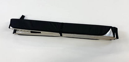 Folded insulated window cover secured with a black strap, revealing the reflective silver interior edges.