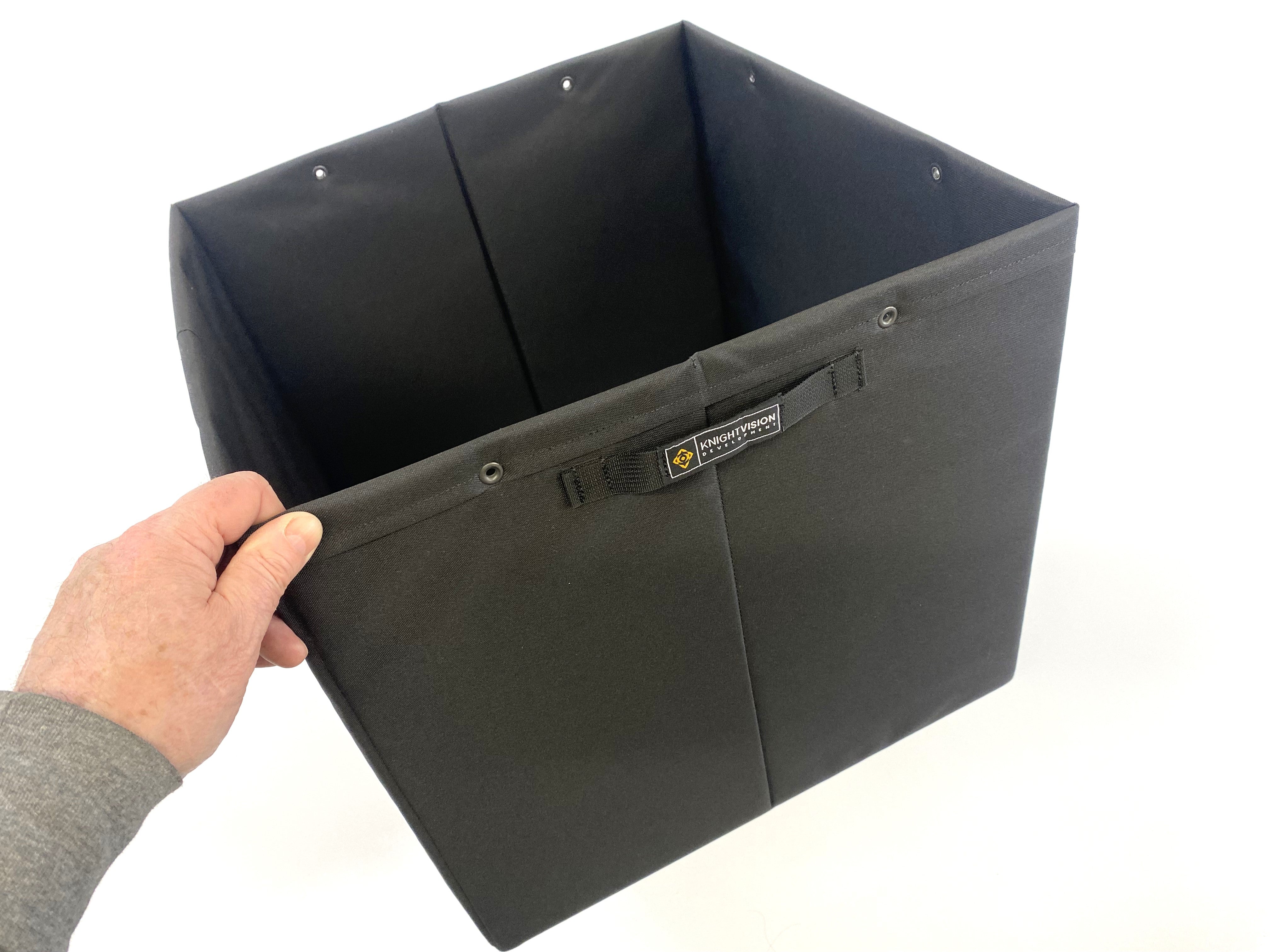 Hand holding open-top black Knight Vision storage bin with interior snaps and front label