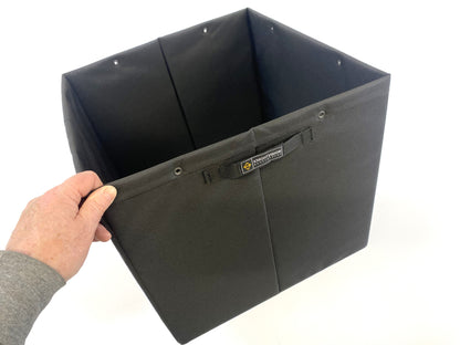 Hand holding open-top black Knight Vision storage bin with interior snaps and front label