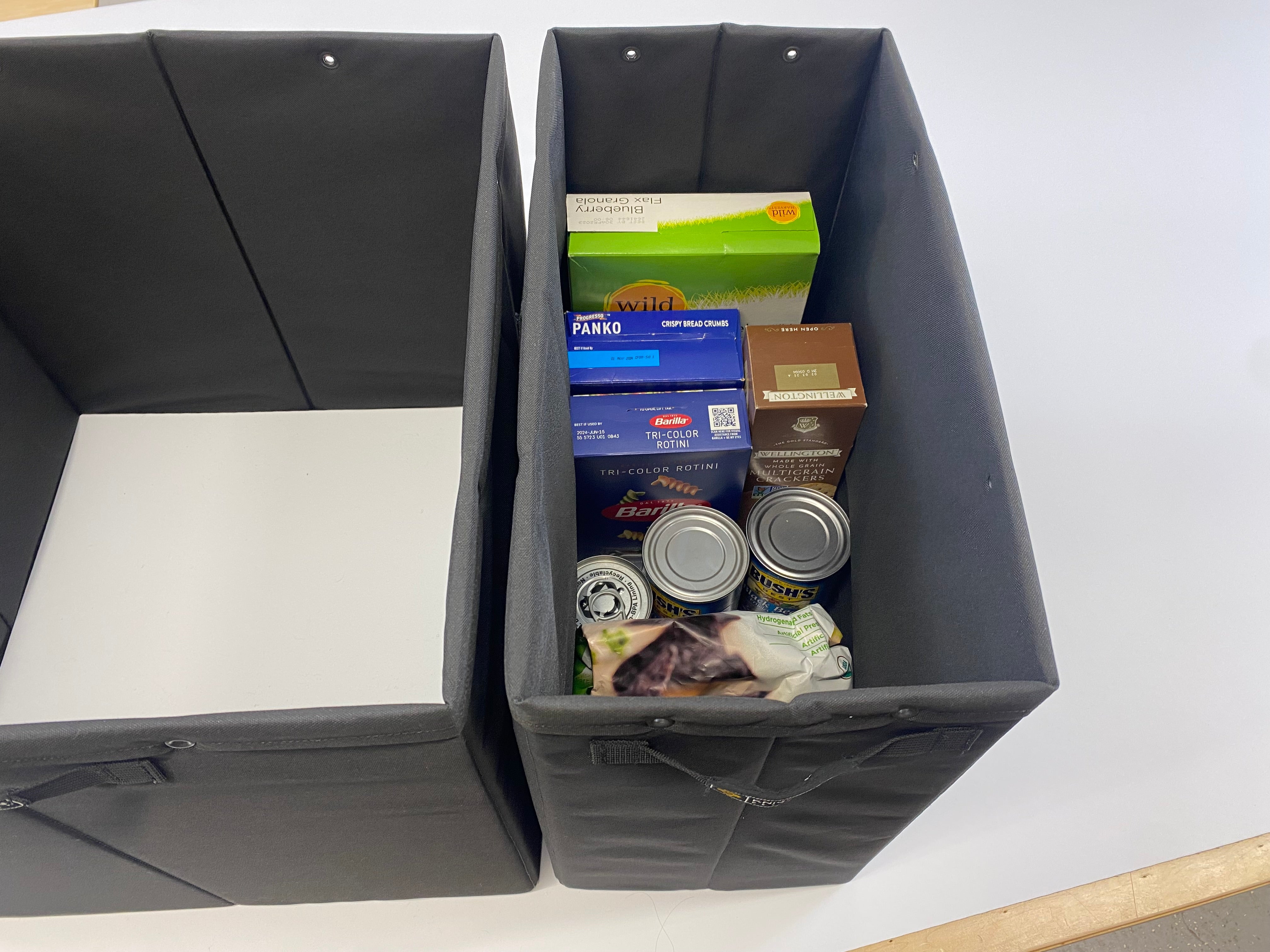 Knight Vision black storage bin filled with groceries next to an empty matching bin on white surface
