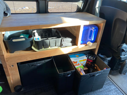 Wooden shelving unit in van with Knight Vision storage bins, snacks, water container, and hygiene items