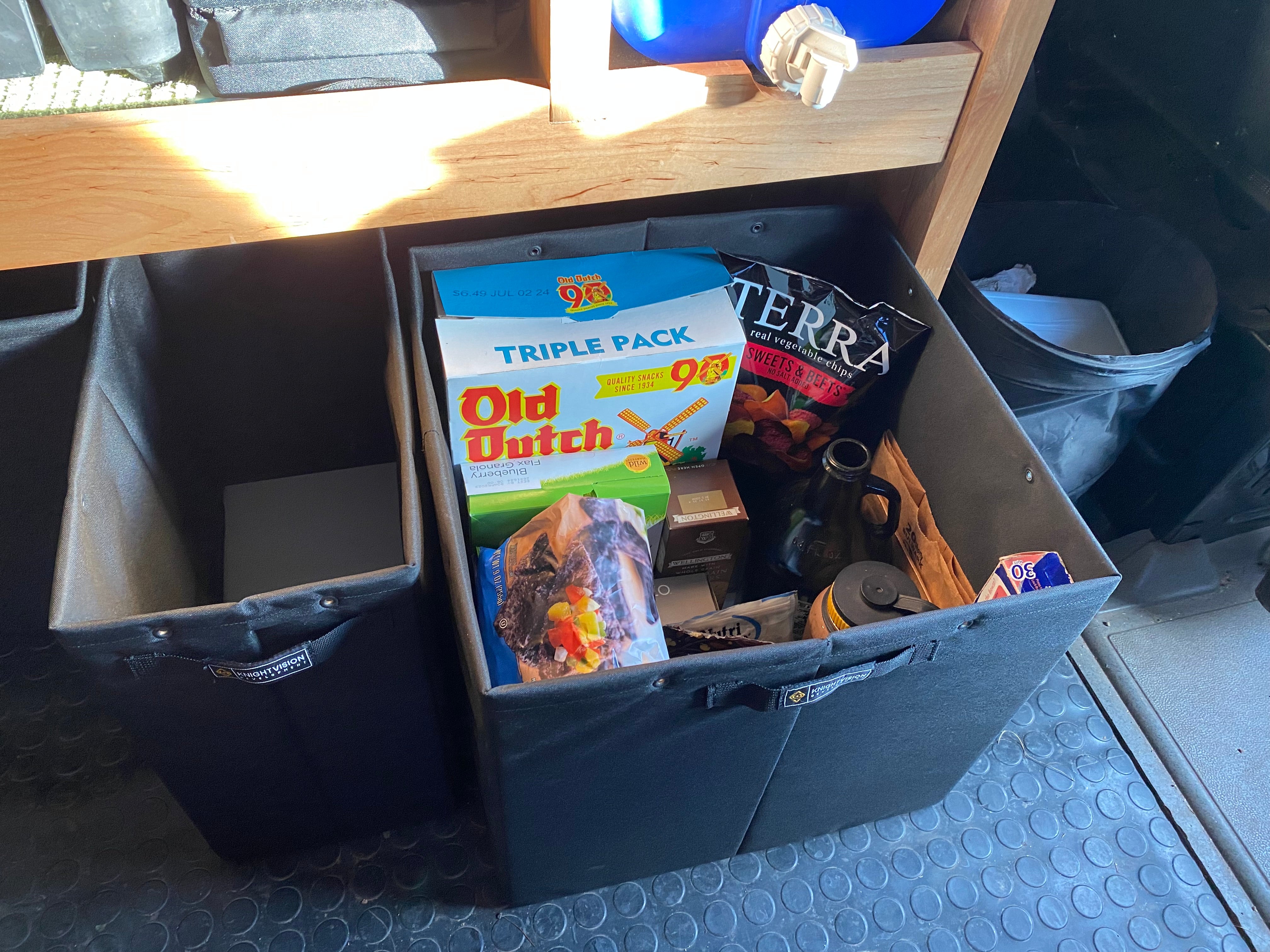 Black Knight Vision storage bin full of snacks and groceries next to an empty bin under a wooden shelf
