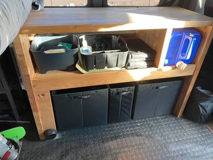 Three Knight Vision storage bins organized neatly under a wooden shelf inside a van setup