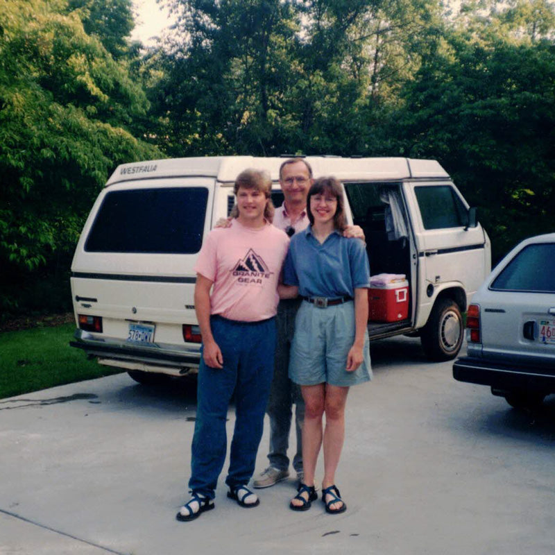 Jeff and Lisa Knight stand with a family member in front of a white Volkswagen Westfalia van.