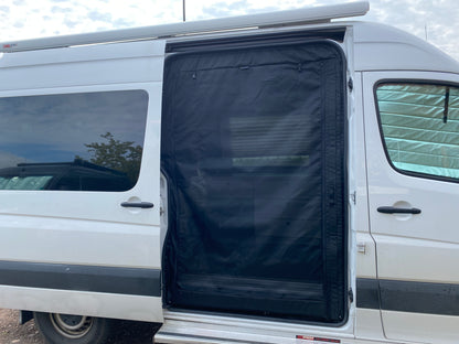 Black bug screen installed in the open sliding door of a white Sprinter van, providing ventilation while keeping insects out.