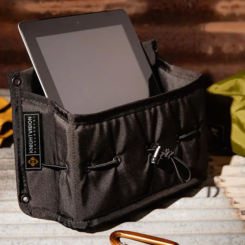 This image shows The Spice Cache by Knight Vision Development in use as a multi-purpose storage pouch, holding a tablet (iPad). It highlights the product's versatility—ideal for organizing electronics, gear, or tools in a van, garage, or outdoor setup. The cinch cord loops and rugged build reinforce its utility for adventure or everyday use.