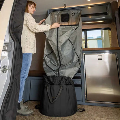 A woman unzipping the portable shower system hanging inside an adventure van.