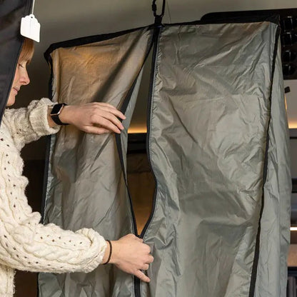 Opening the curtain of the portable shower system inside the camper van.